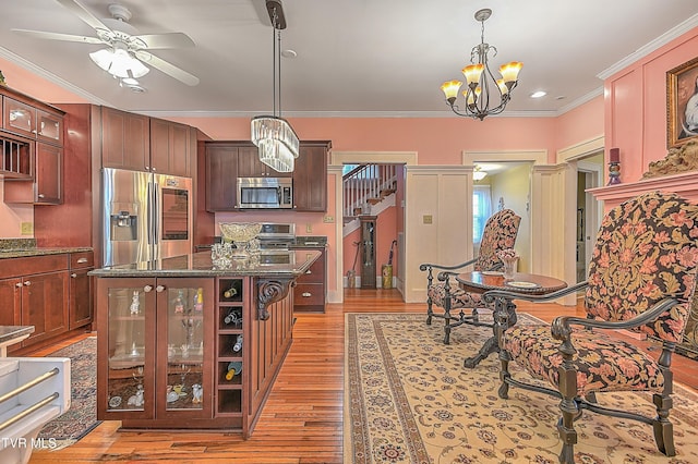 kitchen with hanging light fixtures, crown molding, stainless steel appliances, and a kitchen island