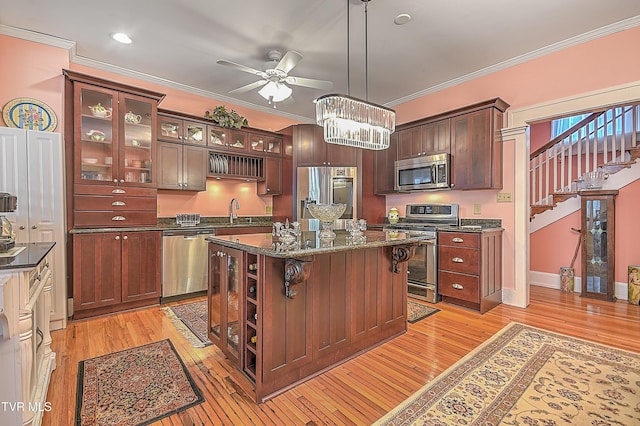 kitchen featuring a breakfast bar, pendant lighting, ornamental molding, a center island, and stainless steel appliances