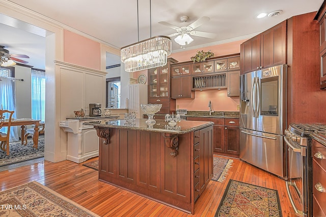 kitchen with appliances with stainless steel finishes, decorative light fixtures, a breakfast bar area, ornamental molding, and a center island