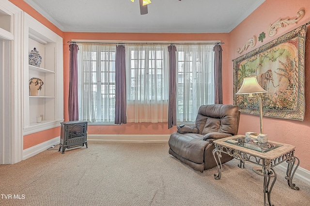 living area with a wood stove, ornamental molding, carpet, ceiling fan, and built in shelves