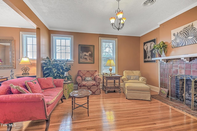 living room featuring crown molding, wood-type flooring, a fireplace, and a textured ceiling