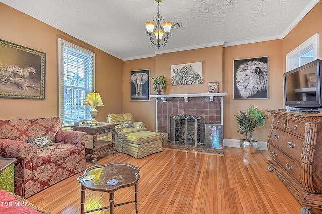 living room featuring a tile fireplace, ornamental molding, wood-type flooring, and a textured ceiling