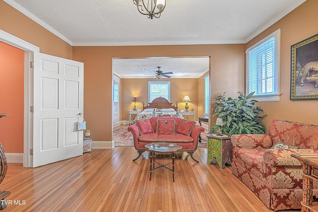 interior space with ornamental molding, ceiling fan, a textured ceiling, and light hardwood / wood-style flooring