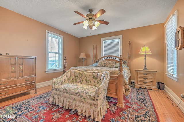 bedroom with ceiling fan, light hardwood / wood-style floors, and a textured ceiling