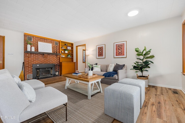 living room with built in features, hardwood / wood-style floors, and a wood stove