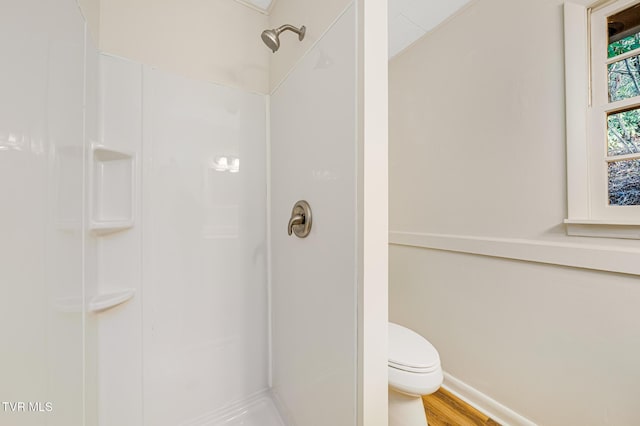 bathroom featuring a shower, hardwood / wood-style flooring, and toilet