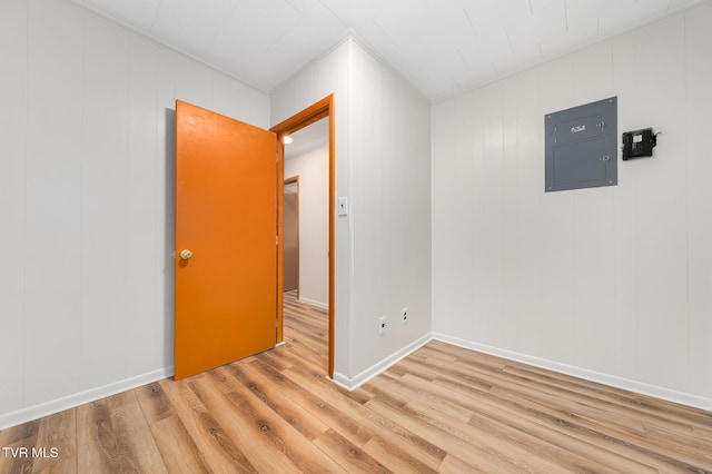 spare room featuring electric panel and light hardwood / wood-style flooring