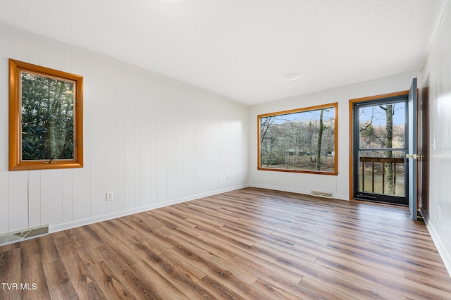 spare room with light hardwood / wood-style floors and a textured ceiling