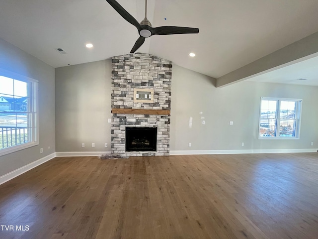 unfurnished living room with ceiling fan, dark hardwood / wood-style flooring, a stone fireplace, and vaulted ceiling