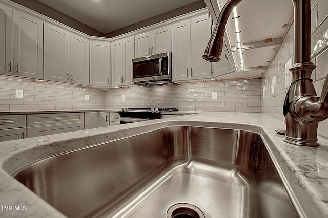 interior space with light stone counters, appliances with stainless steel finishes, backsplash, and white cabinets