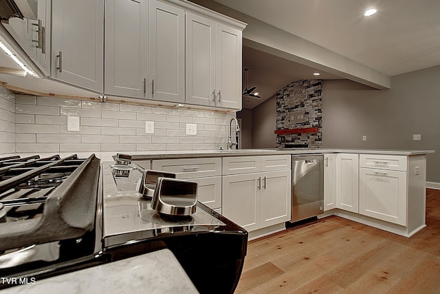 kitchen featuring sink, white cabinets, stainless steel dishwasher, kitchen peninsula, and light hardwood / wood-style flooring