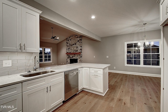 kitchen featuring sink, white cabinets, decorative light fixtures, stainless steel dishwasher, and kitchen peninsula