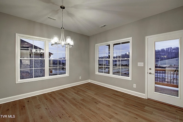 unfurnished dining area featuring hardwood / wood-style flooring and a chandelier