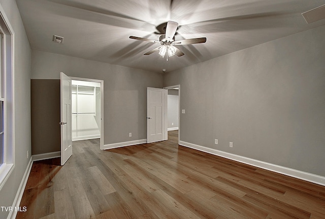 unfurnished bedroom featuring ceiling fan, a spacious closet, and light hardwood / wood-style floors