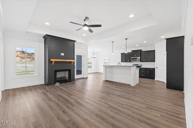 unfurnished living room featuring a fireplace, dark hardwood / wood-style flooring, a raised ceiling, and ceiling fan