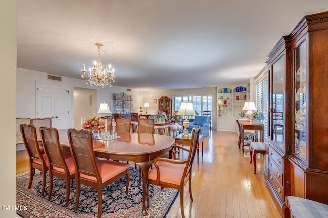 dining space featuring light hardwood / wood-style flooring and a notable chandelier