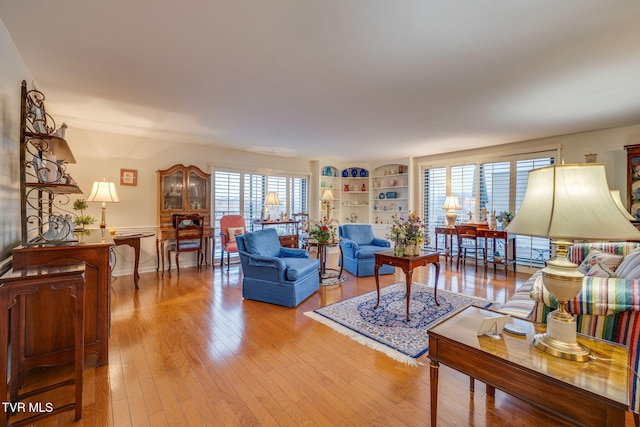 living room with built in shelves, a healthy amount of sunlight, and light wood-type flooring