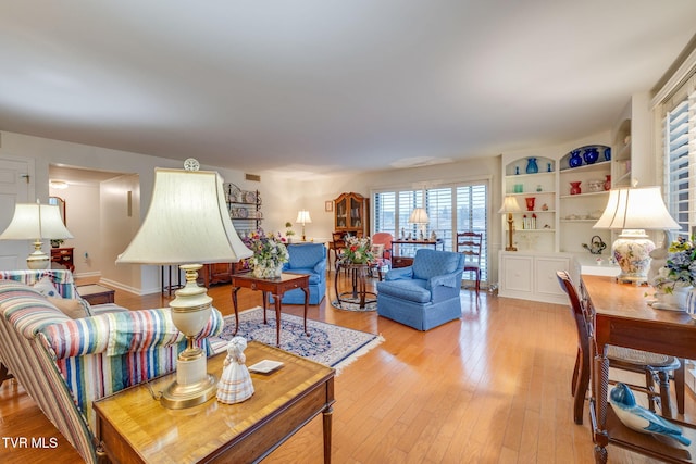 living room with built in features and light hardwood / wood-style floors