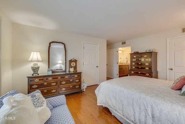 bedroom featuring connected bathroom and light hardwood / wood-style flooring