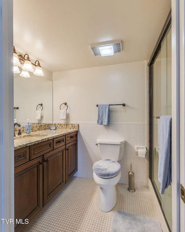 bathroom featuring toilet, vanity, tile patterned floors, and tile walls