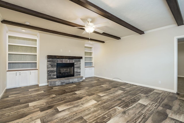 unfurnished living room featuring beam ceiling, built in shelves, ceiling fan, dark wood-type flooring, and a fireplace