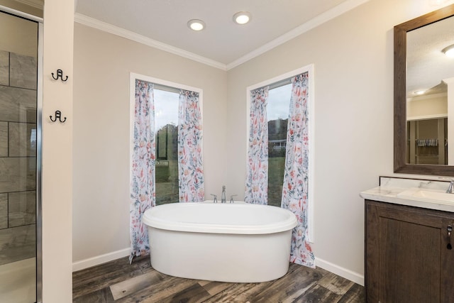 bathroom with a washtub, vanity, hardwood / wood-style flooring, and ornamental molding