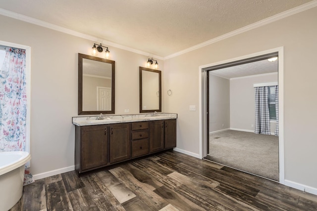 bathroom with a tub to relax in, vanity, a textured ceiling, crown molding, and hardwood / wood-style flooring