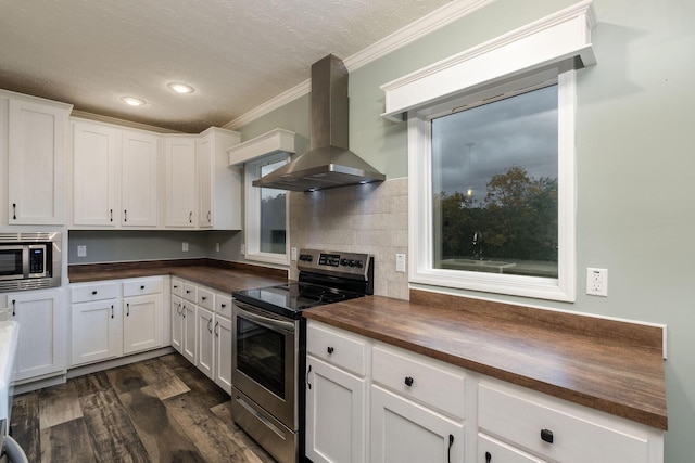 kitchen with exhaust hood, appliances with stainless steel finishes, butcher block countertops, dark hardwood / wood-style flooring, and white cabinetry