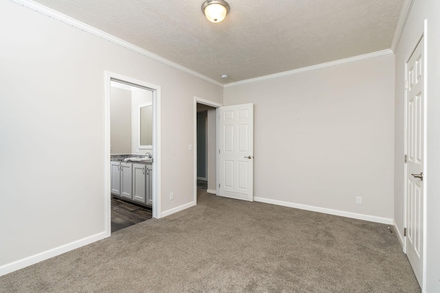 unfurnished bedroom with ensuite bathroom, dark carpet, ornamental molding, and a textured ceiling