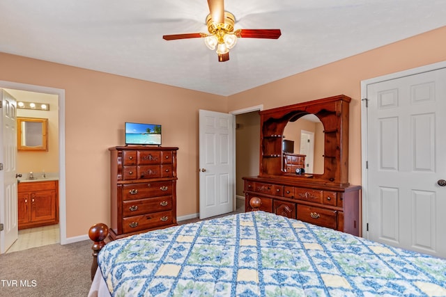 bedroom with ceiling fan, light colored carpet, sink, and ensuite bath