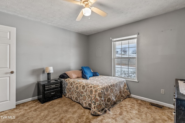 bedroom featuring ceiling fan, light carpet, and a textured ceiling