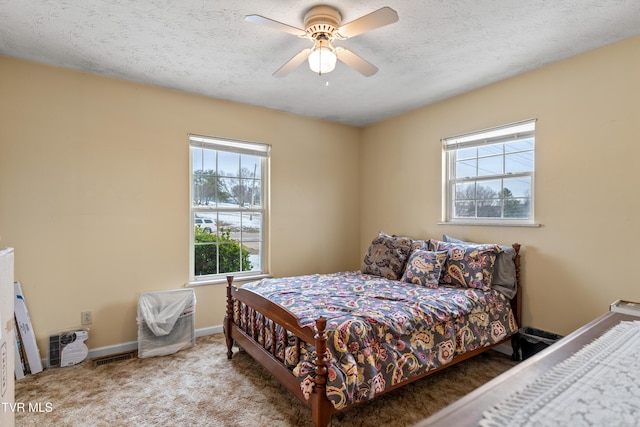 carpeted bedroom featuring ceiling fan and a textured ceiling