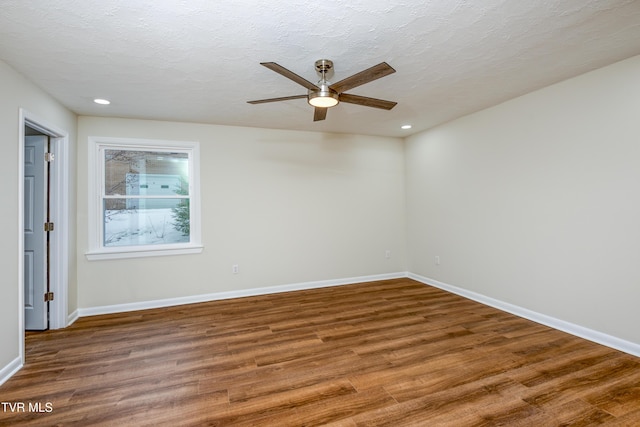 empty room featuring a textured ceiling, ceiling fan, and dark wood-type flooring