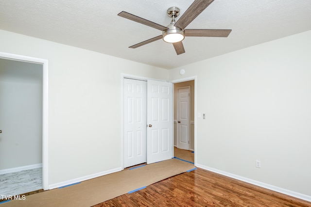 unfurnished bedroom with hardwood / wood-style floors, a textured ceiling, a closet, and ceiling fan