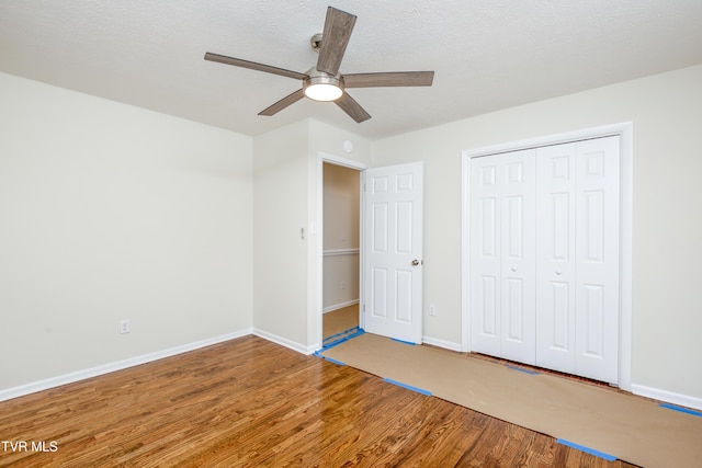 unfurnished bedroom with hardwood / wood-style floors, ceiling fan, a textured ceiling, and a closet