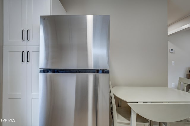 kitchen featuring stainless steel fridge, a breakfast bar area, and white cabinets