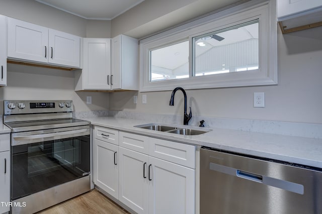 kitchen featuring appliances with stainless steel finishes, sink, white cabinets, and light hardwood / wood-style flooring