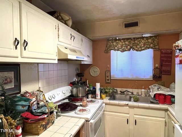 kitchen featuring tasteful backsplash, tile counters, visible vents, white electric range, and under cabinet range hood