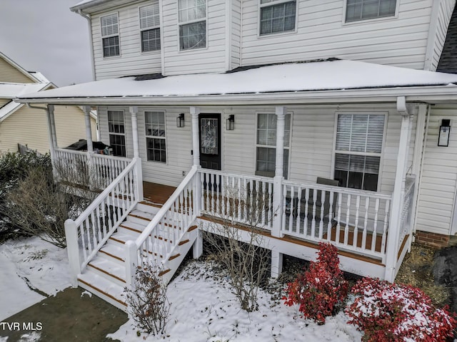 snow covered property entrance with a porch