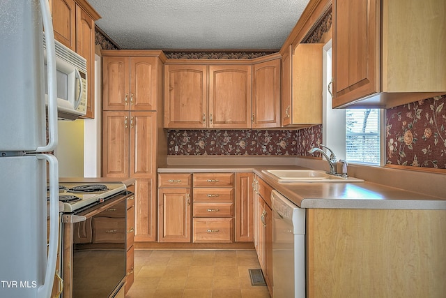 kitchen with a textured ceiling, sink, and white appliances