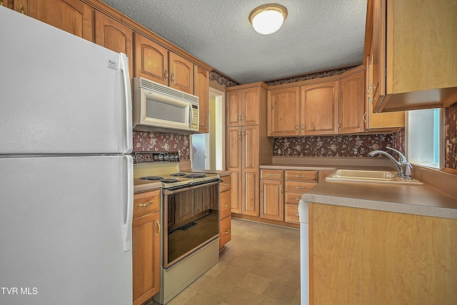 kitchen with a textured ceiling, white appliances, and sink