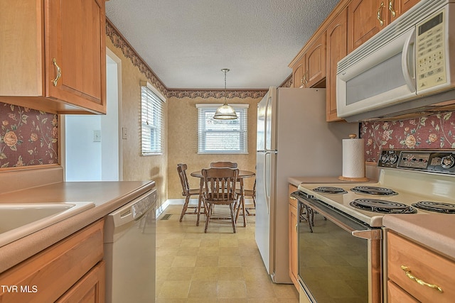 kitchen with a notable chandelier, decorative light fixtures, white appliances, and a textured ceiling