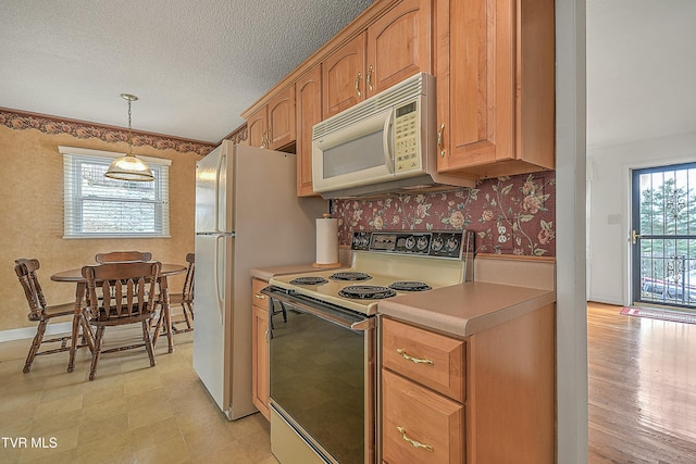 kitchen with a textured ceiling, white appliances, and decorative light fixtures