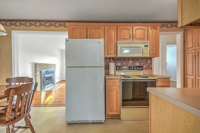 kitchen with a textured ceiling, white appliances, and a stone fireplace