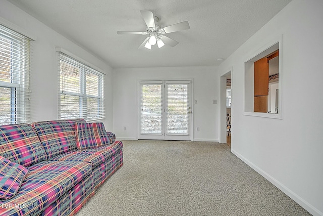 carpeted living room with ceiling fan and a textured ceiling