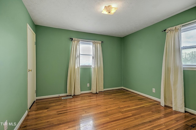 empty room with hardwood / wood-style flooring and a textured ceiling