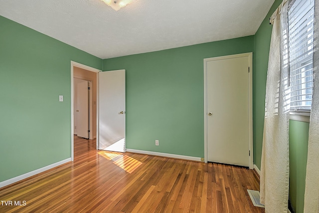 unfurnished bedroom featuring hardwood / wood-style flooring and a textured ceiling