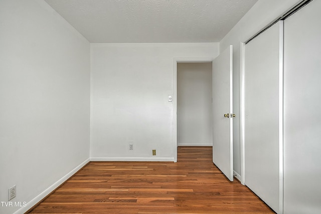 unfurnished bedroom featuring a textured ceiling, hardwood / wood-style flooring, and a closet