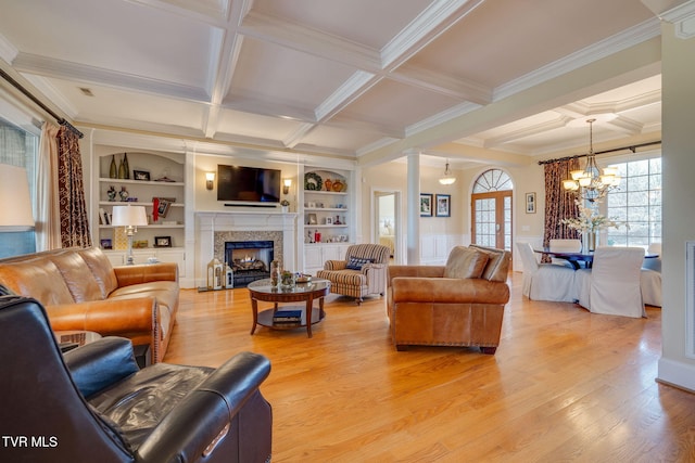 living room featuring coffered ceiling, crown molding, built in features, a notable chandelier, and beam ceiling