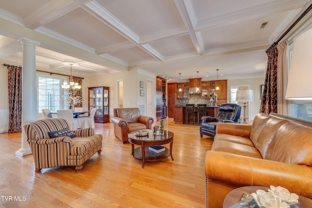 living room with beam ceiling, ornate columns, light hardwood / wood-style flooring, a notable chandelier, and ornamental molding